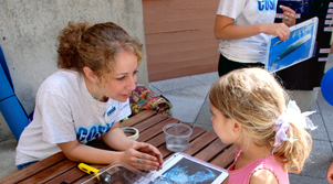 College-age COSIA student talking with a young student at a COSIA ocean festival